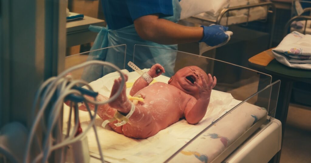 Medical professional holding newborn baby in hospital representing birth injury claims