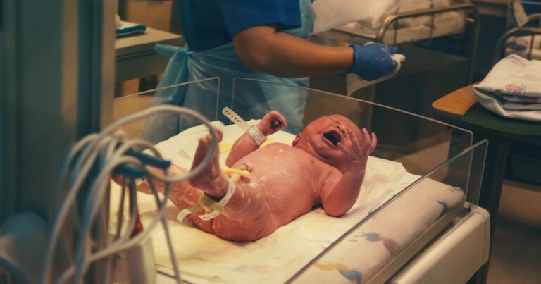 Medical professional holding newborn baby in hospital representing birth injury claims