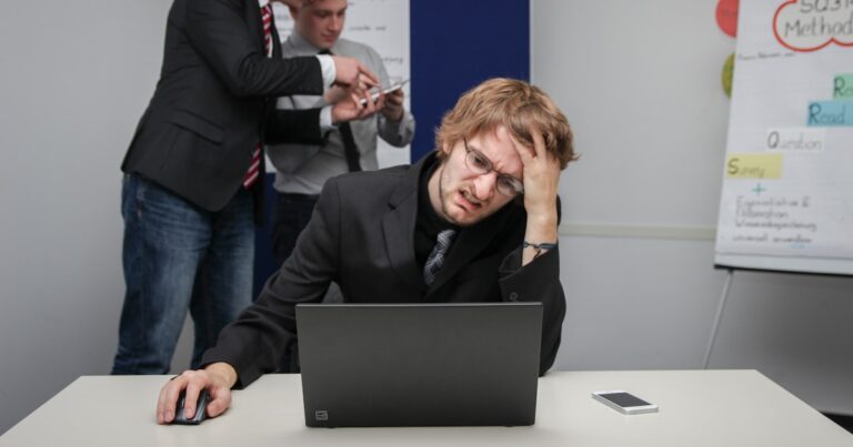 Stressed worker at laptop representing workplace bullying claims in the UK
