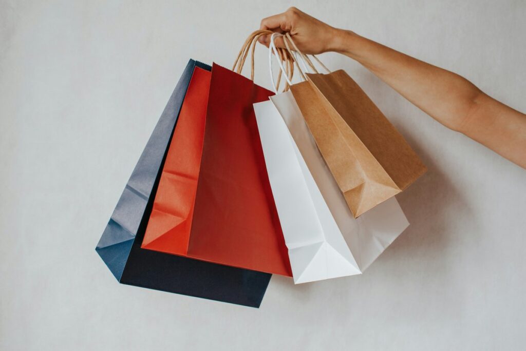 Person holding shopping bags at checkout - Photo by Iuliia Pilipeichenko on Unsplash