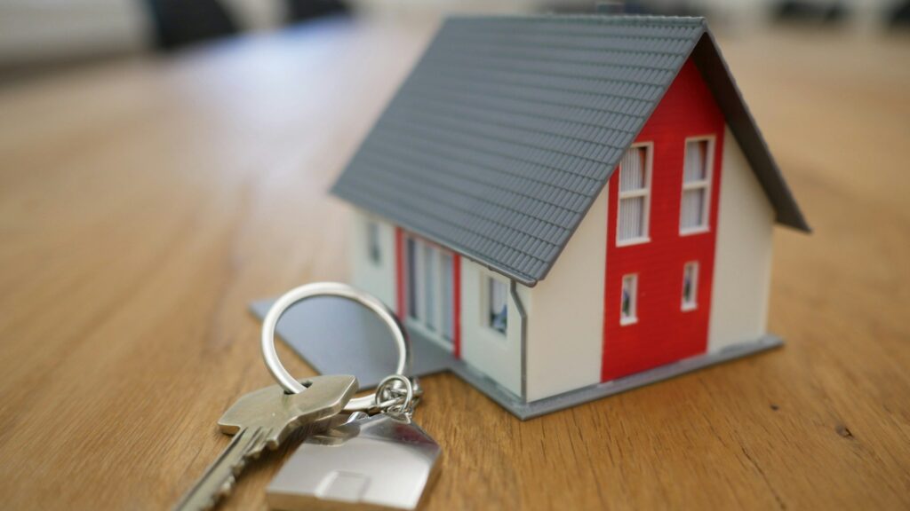 House keys on a table with a miniature home model, symbolizing tenant and landlord disputes