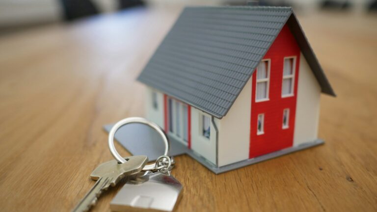 House keys on a table with a miniature home model, symbolizing tenant and landlord disputes