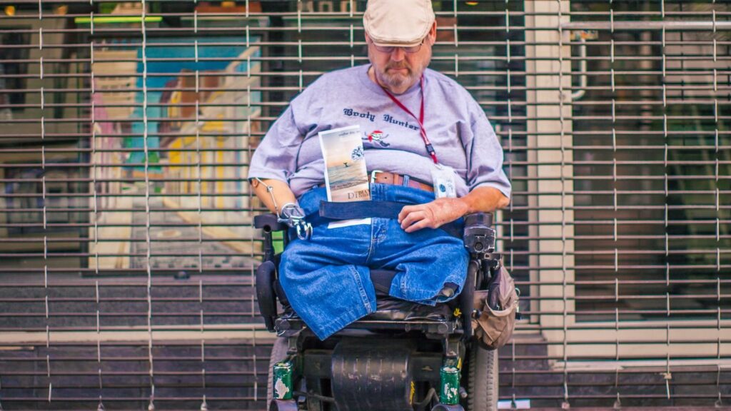 A wheelchair user on a city sidewalk, illustrating public accessibility barriers.