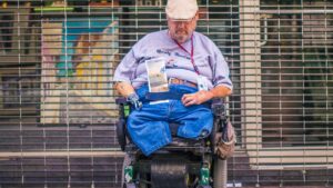 A wheelchair user on a city sidewalk, illustrating public accessibility barriers.
