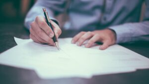 A person signing paperwork at a desk, representing a vendor contract dispute.