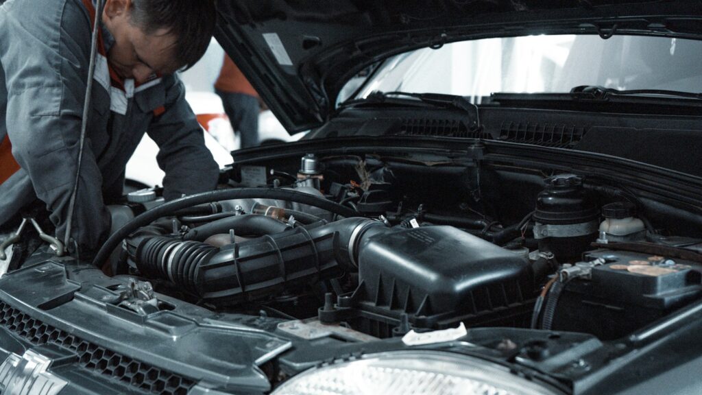 Mechanic inspecting a car engine beneath an open bonnet