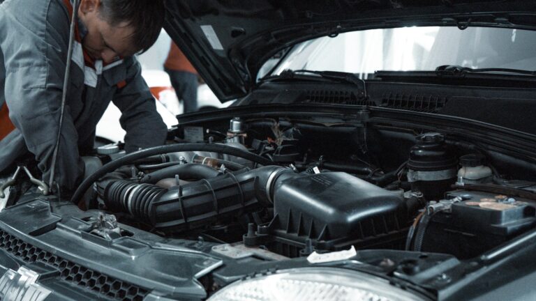 Mechanic inspecting a car engine beneath an open bonnet