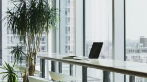 Office desk with a laptop beside large windows